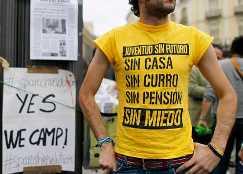 Un muchacho con una camiseta en la que dice: Juventud sin futuro, sin casa, sin curro, sin pensión, sin miedo 