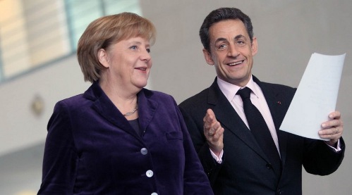 Angela Merkel y Nicolas Sarkozy, muy sonrientes con unos papeles en la mano