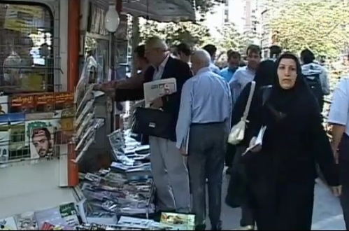 un quiosco de prensa, varios hombres y mujeres tapadas compran prensa