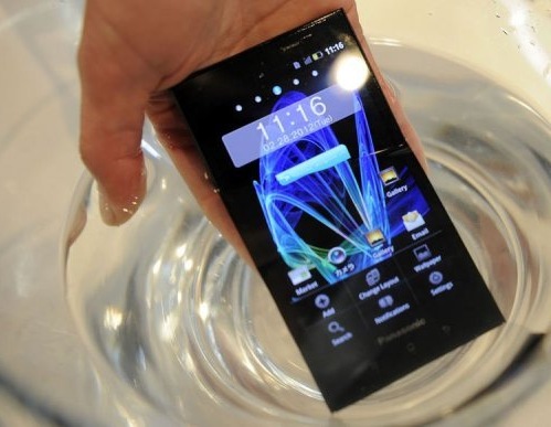 Una mano sostiene un móvil dentro de un vaso de agua