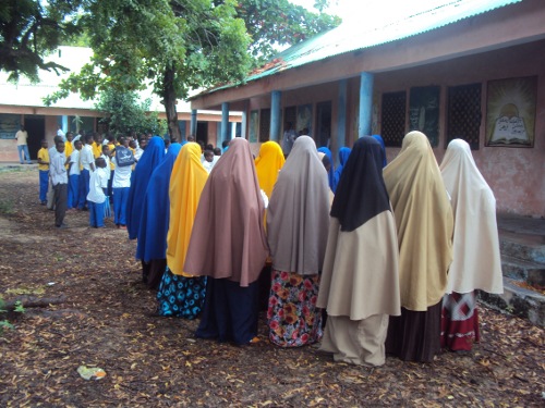 grupo de niños y niñas, con hijab, a la puerta de la escuela