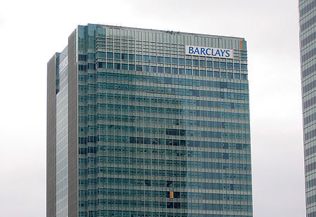Parte superior de un edificio de cristal donde está el cartel de Barclays