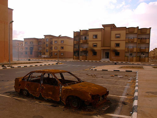Un coche quemado ante un edificio deshabitado (Libia)