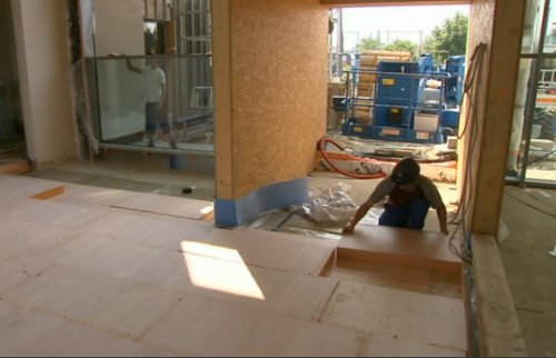 Un trabajador pone unas grandes placas en el suelo de un edificio en construcción