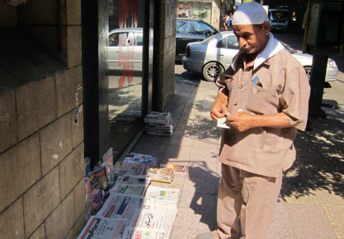 Un hombre delante de un puesto de periódicos