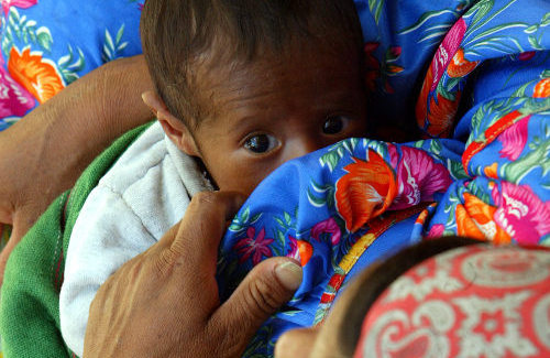 Un bebé indígena en brazos de su madre mira a la cámara