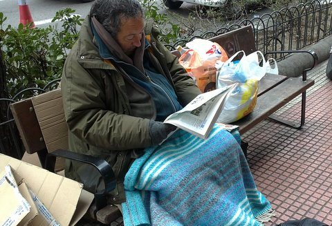 Un mendigo leyendo un periódico