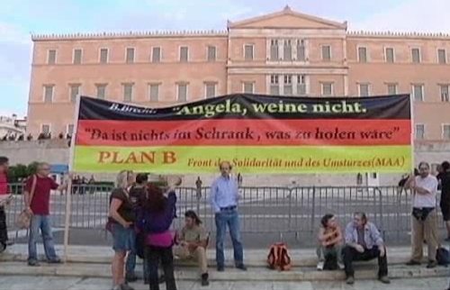 Manifestantes con una pancarta contra la visita de Merkel