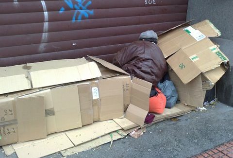 Un hombre durmiendo en la calle tapado por cartones