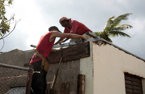 Dos hombres arreglan techos tras paso del Sandy
