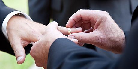 Dos hombres colocándose anillo de casados