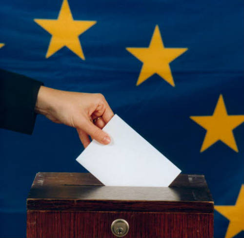 Mano de un votante con la bandera europea al fondo