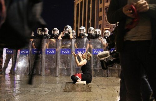 Una mujer en el suelo delante de una barrera de antidisturbios