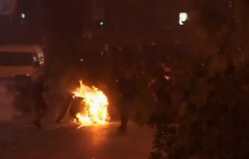 Manifestantes en la oscuridad en la que se ve algo ardiendo