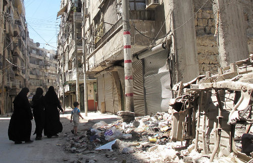 Unas mujeres caminan por una calle con restos de edificios destruidos