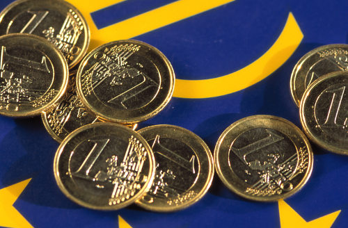 Monedas de euro sobre la bandera de la UE