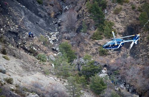 Lugar del accidente, varios rescatadores entre los restos del avión y un helicóptero que sobrevuela