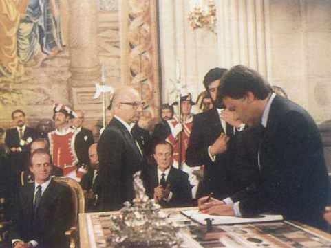 Felipe González firma, al fondo el rey le mira