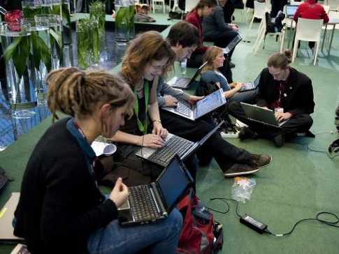 Un grupo de jóvenes sentados de manera informal escriben en sus ordenadores