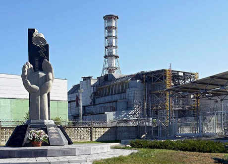 Un momumento conmemorativo y detrás el reactor de Chernobyl