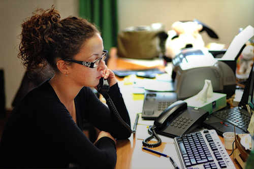 Una mujer hablando por teléfono ante un ordenador