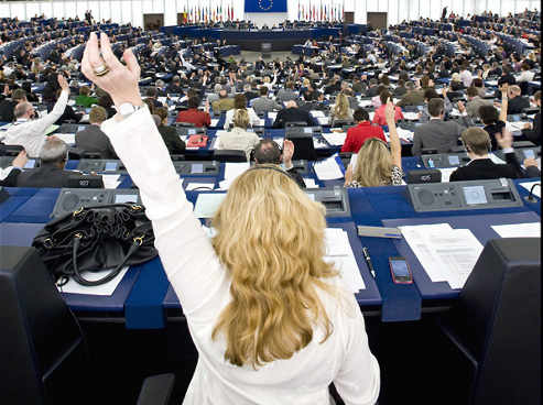pleno del parlamento, una europarlamentaria vota con la mano alzada
