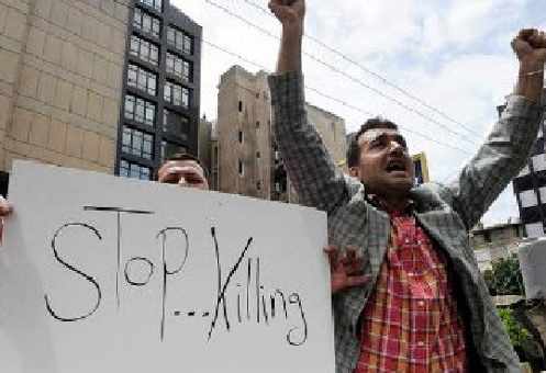 Un hombre muestra una pancarta en la que dice Stop Killing