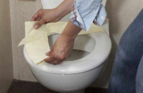 un hombre pone papel higiénico alrededor del váter