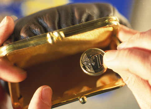 Una mano saca una moneda de euro de un monedero