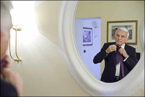 Buzek se hace el nudo de la corbata ante un espejo