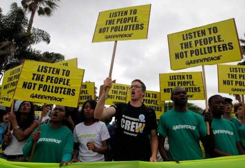 Activistas, muchos con camisetas de Greenpeace protestan