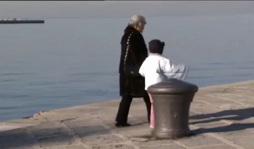 Una persona mayor pasea con una niña cerca del mar