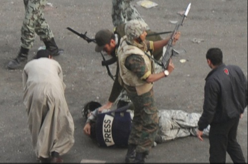 Un periodista en el suelo y militares rodeándolo