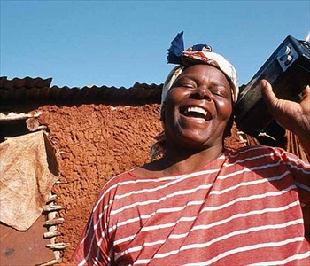 Una mujer africana con una gran sonrisa escucha la radio