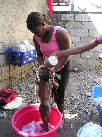 Una mujer lava a un pequeño en un balde