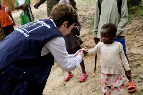 La comisaria de Ayuda humanitaria da la mano a una niña