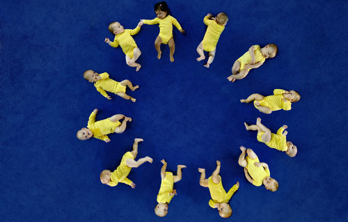 Bebés, sobre fondo azul, formando las estrellas de la bandera de Europa 