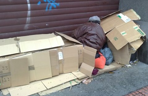 Un hombre durmiendo tapado con cartones