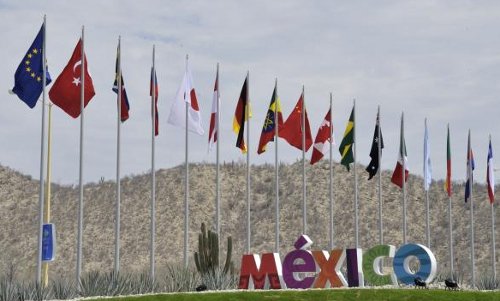 Banderas de los países del G-20 y el nombre de México en medio de un lugar desértico