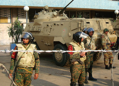 Militares armados delante de un carro de combate