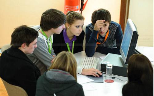 Un grupo de estudiantes universitarios preparan un proyecto alrededor de una mesa y un ordenador