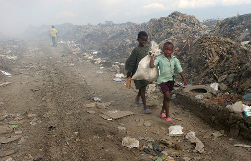 Dos niños llevan unos sacos con objetos rescatados de un vertedero 