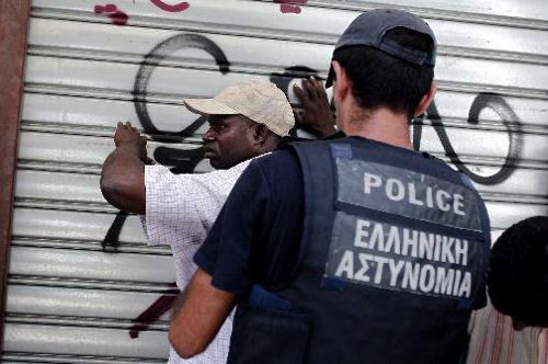 Inmigrante detenidos contra una persiana por la policía griega