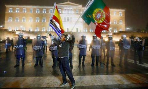 Un manifestante griego con banderas de Grecia, España y Portugal