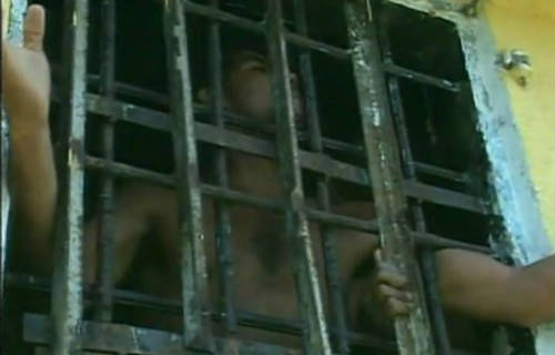 Preso gritando entre rejas en una cárcel latinoamericana