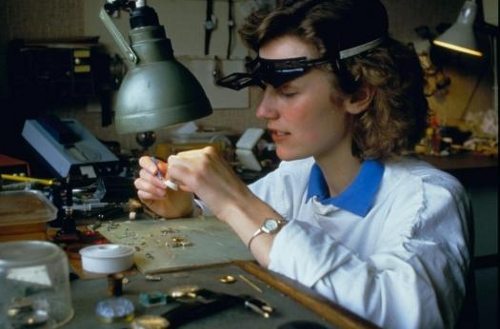 Una joven arregla un reloj en un taller