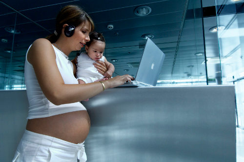 Embarazada con un bebé trabajando en el ordenador