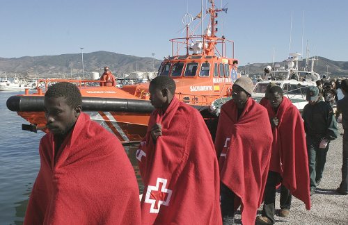 inmigrantes con mantas de la Cruz Roja