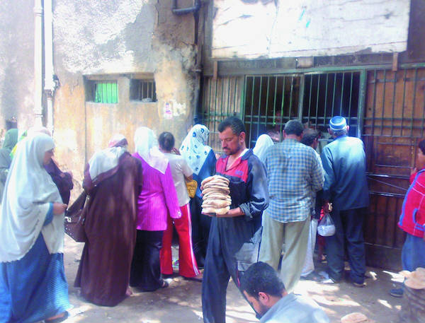 Un grupo de personas hacen cola para obtener alimentos subsidiados en Egipto