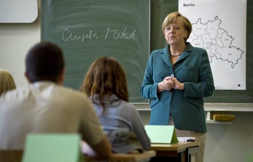 Merkel en un aula ante los estudiantes. En la pizarra su nombre
